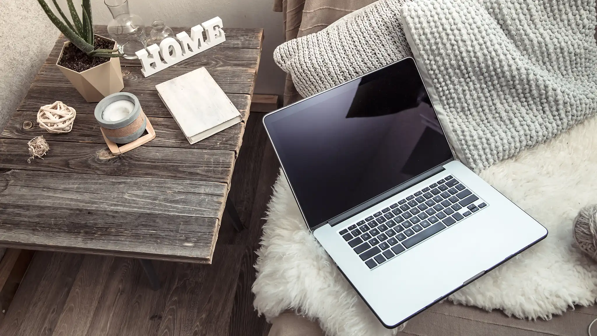 A sofa with a fur blanket and laptop